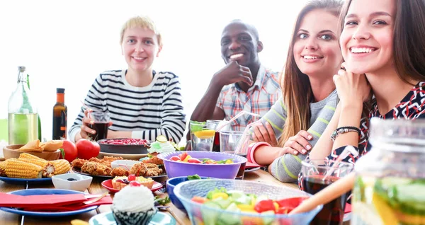 Bir grup insan ahşap masada otururken birlikte yemek yiyorlar.