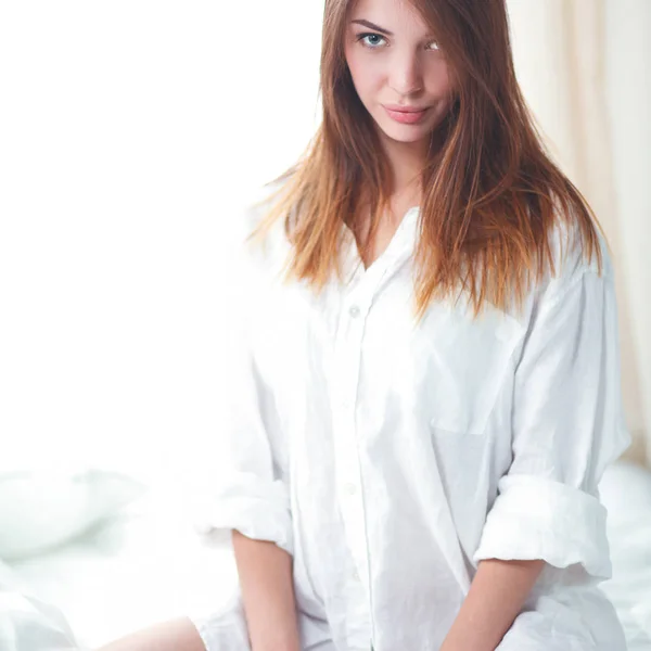 彼女は白いベッドの上に座って美しい女性の肖像画 — ストック写真