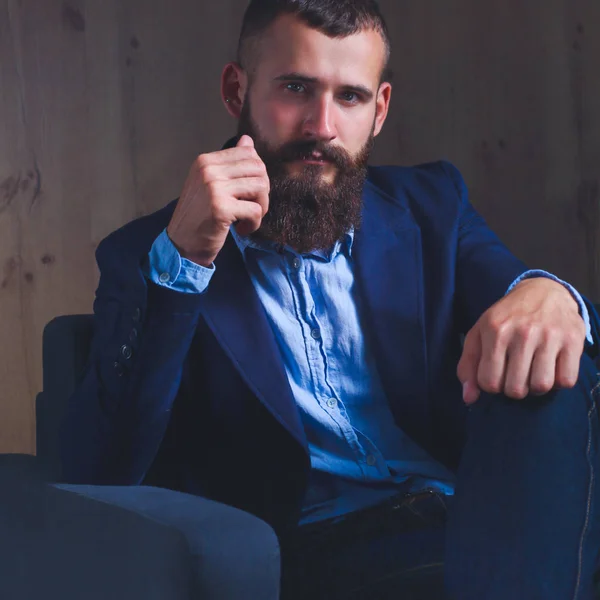 Businessman sitting the sofa in office lobby, isolated on dark — Stock Photo, Image