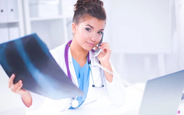 Vrouwelijke arts op zoek x-ray scan en praten over telefoon in diagno — Stockfoto
