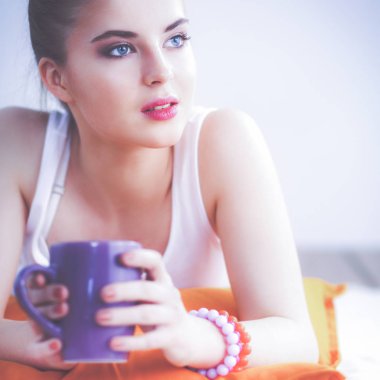 Yastık ile bir yerde yatarken gülümseyen genç kadın