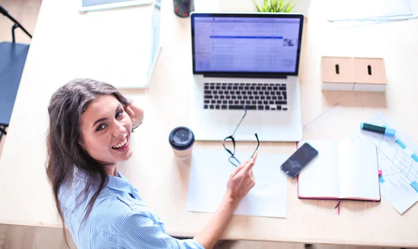 Молода жінка сидить за офісним столом з ноутбуком — стокове фото
