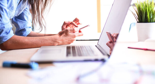 Молодая женщина сидит за рабочим столом с ноутбуком