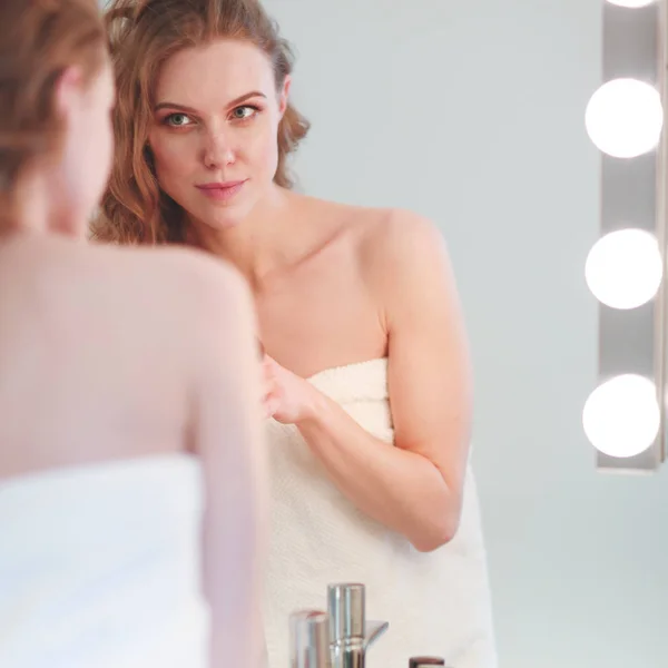 Молода жінка дивиться у дзеркало і одягає макіяж — стокове фото
