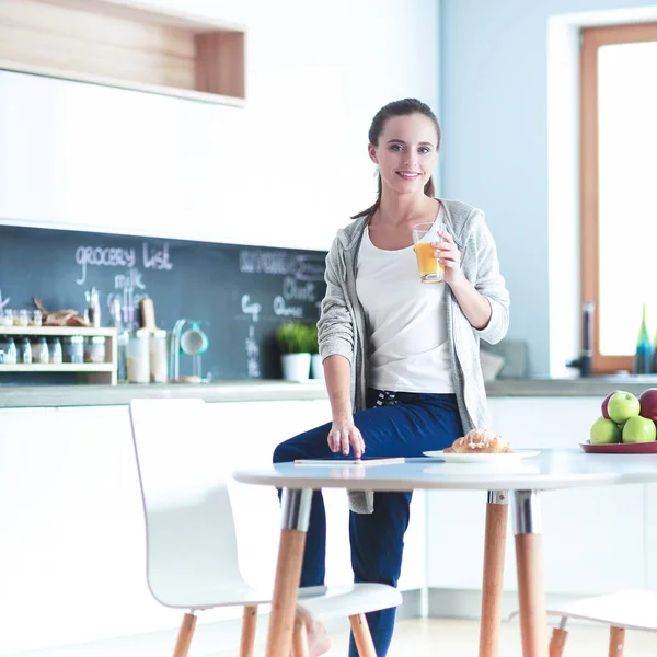 Молодая женщина с апельсиновым соком и таблетками на кухне — стоковое фото