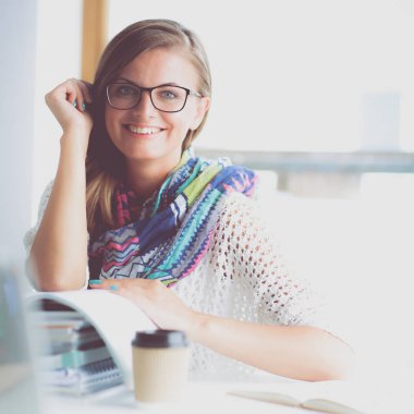 Kitapların arasında masa başında oturan genç bir kadın.