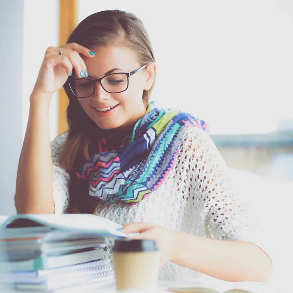 Mujer joven sentada en un escritorio entre libros — Foto de Stock