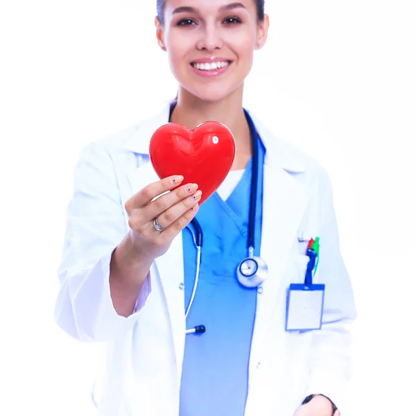 Positive female doctor standing with stethoscope and red heart symbol — Stock Photo, Image