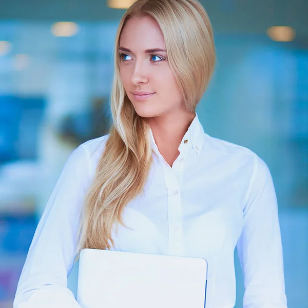 Jonge zakenvrouw staat in business center met laptop — Stockfoto