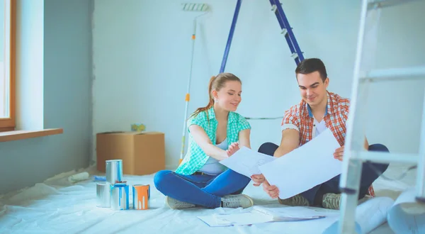 Junges Paar sitzt auf dem Boden und rechnet über seine Ersparnisse — Stockfoto