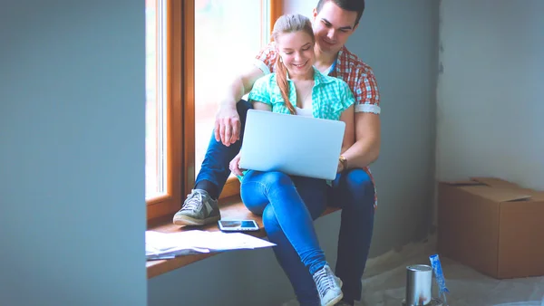 Pareja joven sentada en el suelo y calculando sobre sus ahorros — Foto de Stock