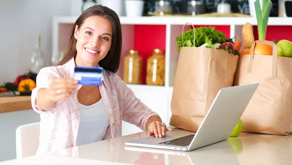 Smiling woman online shopping using tablet and credit card in kitchen — Stock Photo, Image