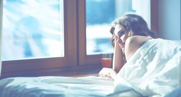 Nő az ágyban fekve, a kora reggeli órákban közelében ablak — Stock Fotó