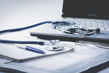 Masasında dosya ve dizüstü bilgisayarla steteskop.