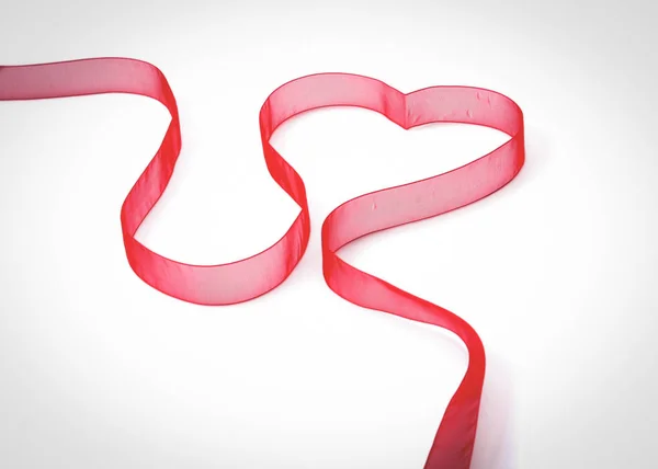 Un corazón con forma de cinta roja, aislado sobre fondo blanco —  Fotos de Stock