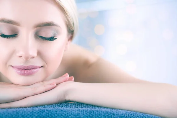 Jovem deitada em uma mesa de massagem, relaxando com os olhos fechados — Fotografia de Stock