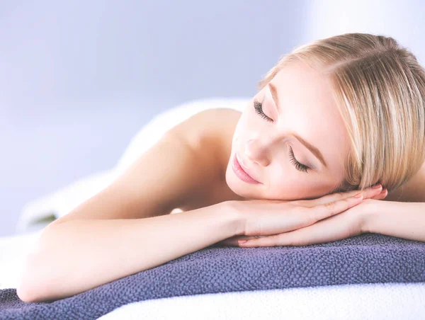 Jovem deitada em uma mesa de massagem, relaxando com os olhos fechados — Fotografia de Stock