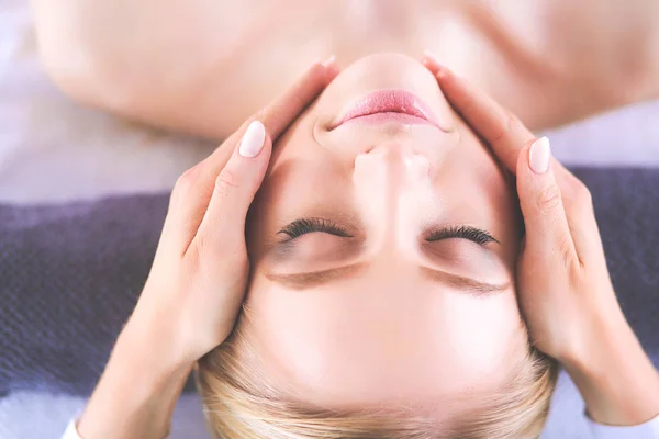 Jovem deitada em uma mesa de massagem, relaxando com os olhos fechados — Fotografia de Stock