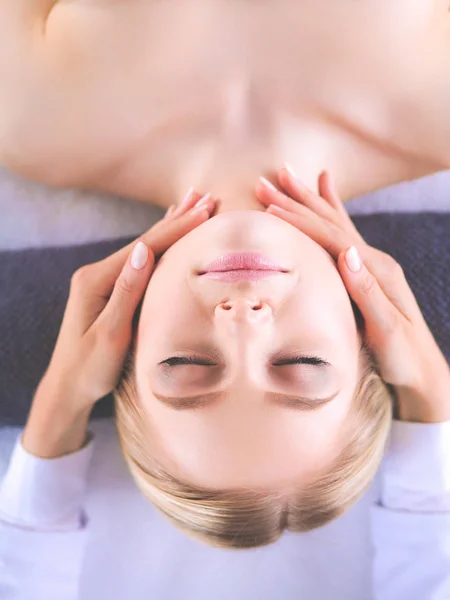 Mujer joven acostada en una mesa de masaje, relajándose con los ojos cerrados — Foto de Stock