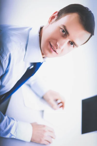 Бизнесмен сидит за столом в офисном холле, используя ноутбук — стоковое фото