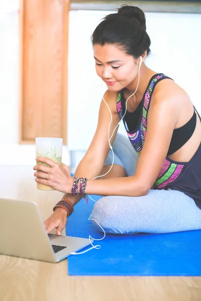 Deportiva mujer sonriente utilizando el ordenador portátil en habitación luminosa — Foto de Stock