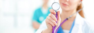 Steteskoplu kadın doktor hastanede bizi dinliyor.