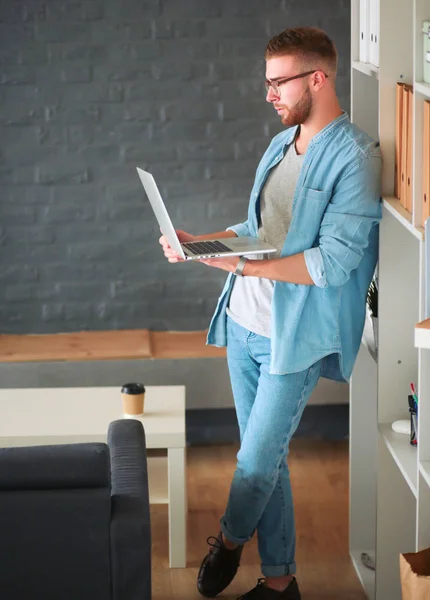 Jongeman houdt laptop staan in de buurt muur — Stockfoto