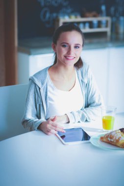 Mutfakta portakal suyu ve tableti olan genç bir kadın..