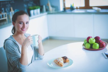 Mutfak masasında tatlı kruvasan ile çay içme kadın.