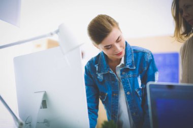 Masanın yanında duran iki genç kadın enstrüman, plan ve dizüstü bilgisayarla.