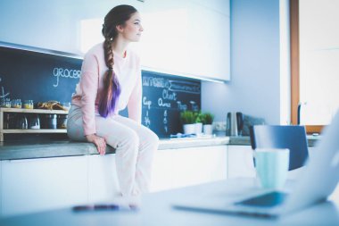 Mutfakta masada oturan genç kadın.