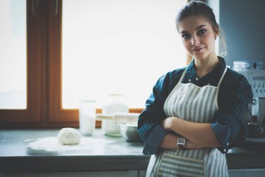 Mutfakta sobanın yanında duran genç bir kadın. .