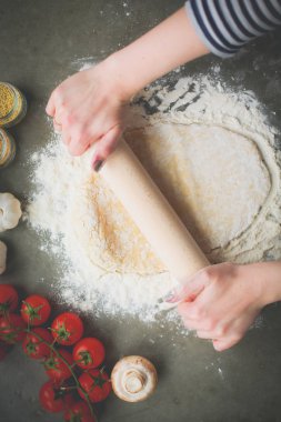 Güzel bir kadın mutfakta pasta pişiriyor. Masanın yanında duruyor..