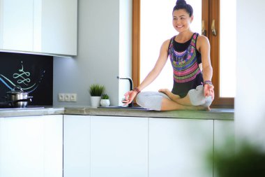 Lotus pozisyonunda mutfak masasında oturan genç güzel kadın. Kadın. Yoga