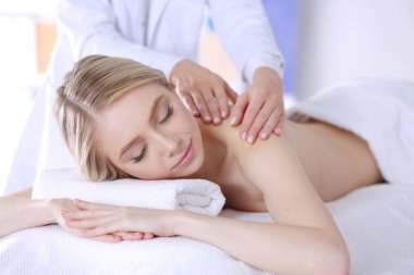 Gözleri kapalı rahatlatıcı bir masaj masanın üzerinde yatan genç kadın.