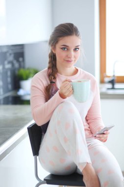 modern mutfakta otururken cep telefonu kullanan kadın.