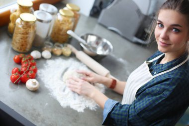 Mutfakta sobanın yanında duran genç bir kadın. .