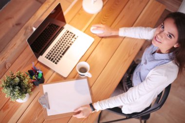 Kupası tutan masasında oturan rahat genç kadın portresi