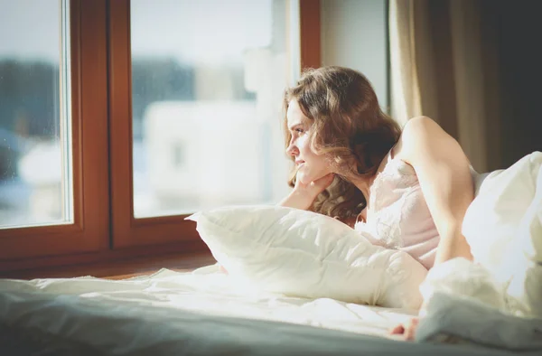 Nő az ágyban fekve, a kora reggeli órákban közelében ablak. — Stock Fotó