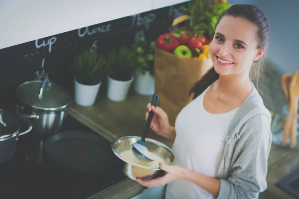 Молодая женщина готовит блины на кухне, стоя возле стола. Женщина на кухне. Кулинария. — стоковое фото