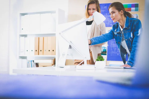 Two young woman standing near desk with instruments, plan and laptop. — Stock Photo, Image