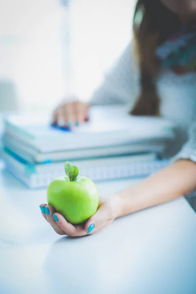 Studentinnen sitzen auf dem Schreibtisch mit Apfel auf einem Stapel Bücher. Student. Hochschule — Stockfoto