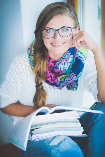 Ung kvinna som sitter vid ett skrivbord bland böcker. Studerande — Stockfoto