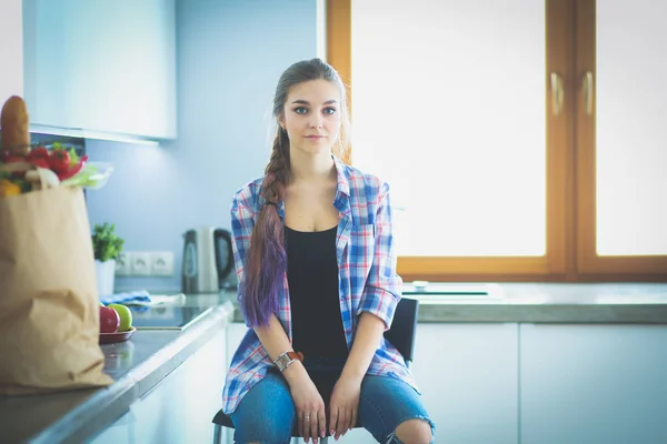 Portrait of young woman standing with arms crossed against kitchen background. — Stock Photo, Image