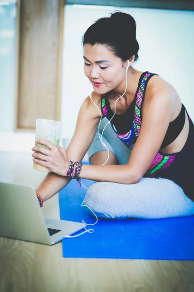 Deportiva mujer sonriente utilizando el ordenador portátil en la habitación luminosa. Una mujer. Estilo de vida — Foto de Stock