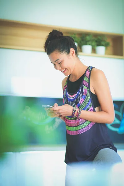 Retrato de una hermosa mujer deportiva usando un teléfono inteligente. Una mujer. Yoga. Deporte — Foto de Stock