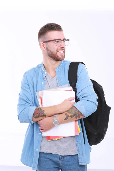 Um estudante do sexo masculino com uma bolsa escolar segurando livros isolados em branco — Fotografia de Stock