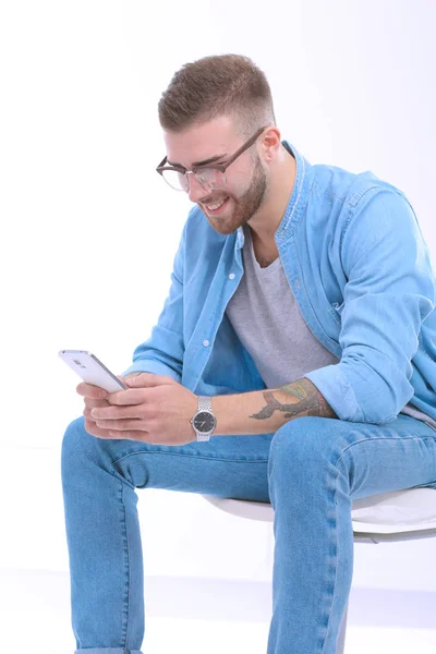 Jeune homme assis sur une chaise et utilisant un téléphone portable. Démarreur. O — Photo