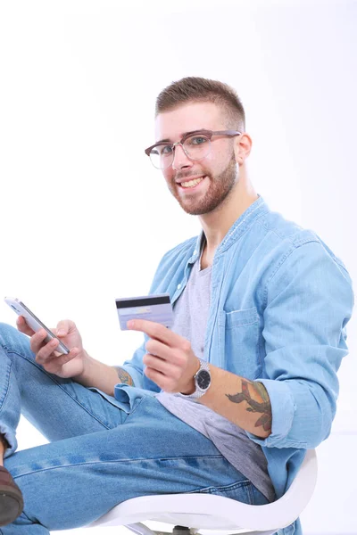 Młody mężczyzna siedzi na krześle i posiadania karty kredytowej. Startupper. — Zdjęcie stockowe
