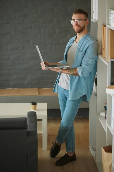 Jongeman houdt laptop staan in de buurt muur. — Stockfoto